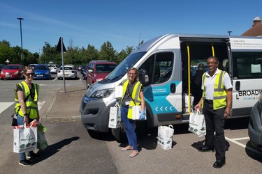 People stand in front of a community minibus